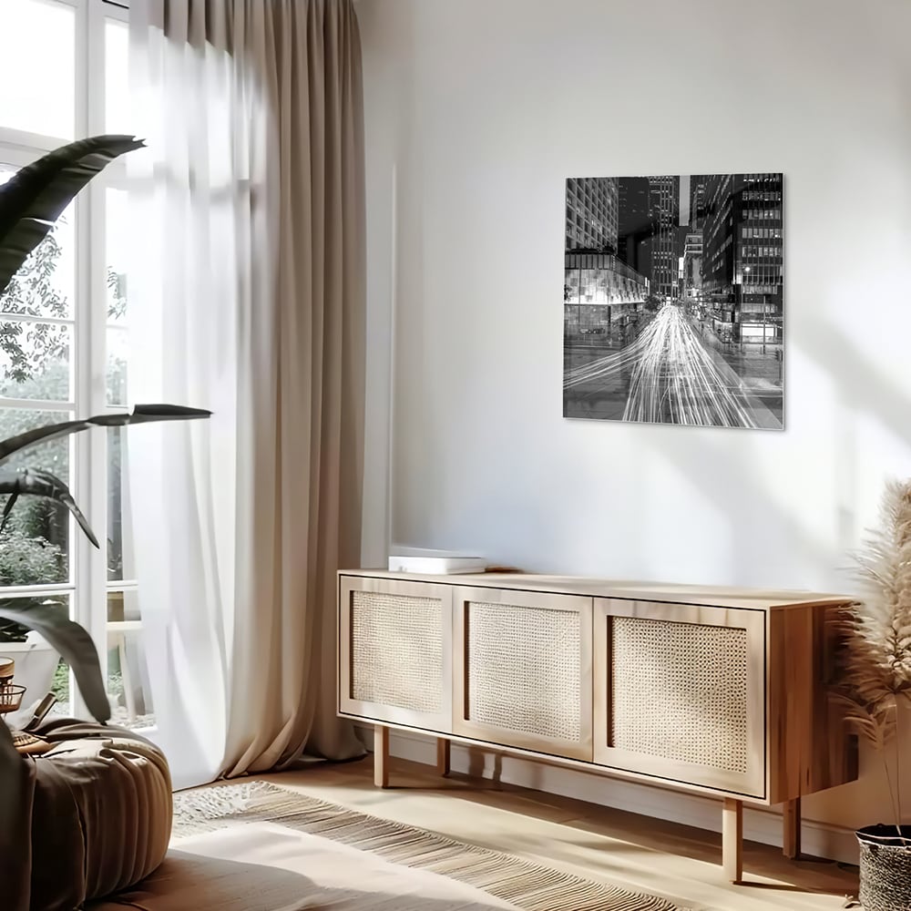 Glazen schilderij met stadslichten in zwart-wit boven een moderne meubelset.
