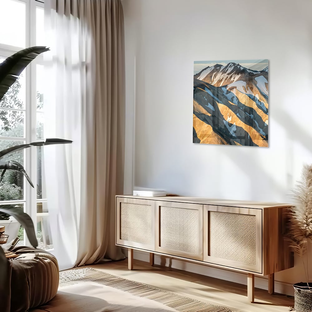 Glazen schilderij van bergen in blauw en goud, hanging in een stijlvolle kamer.