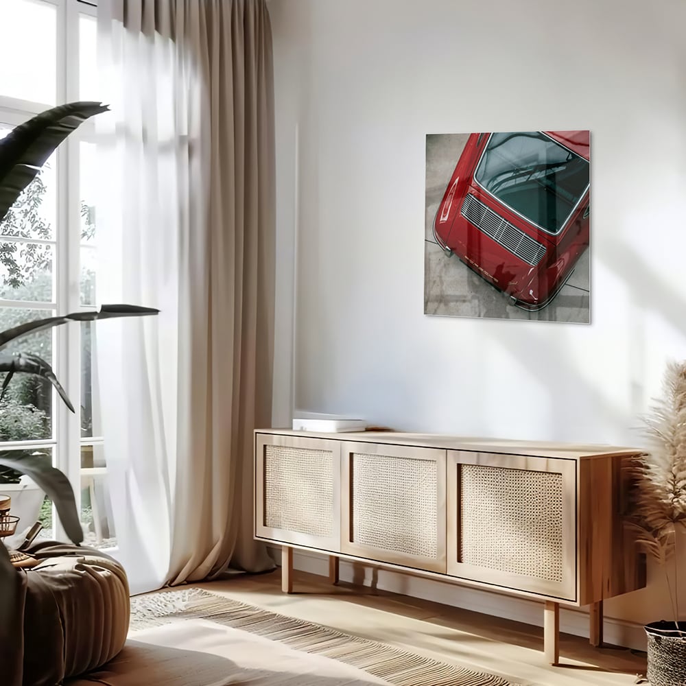Glazen schilderij van een bovenaf gezien rode auto op een muur.