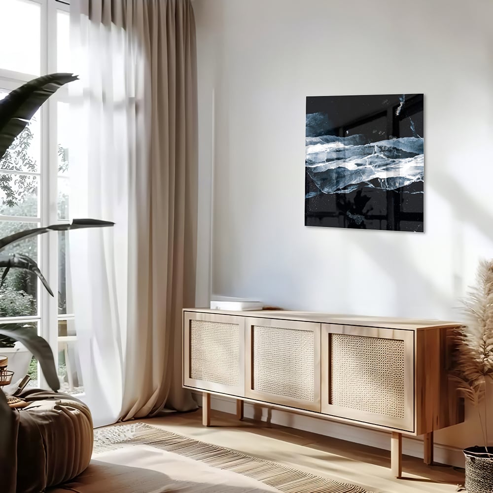 Abstract glazen schilderij in donkere kleuren met blauwe accenten, hangt aan de muur.