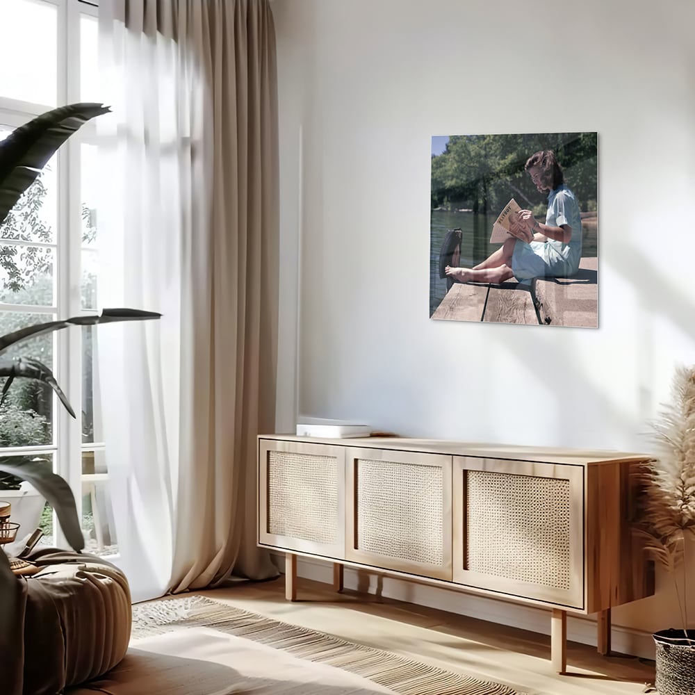Glazen schilderij van een vrouw die aan het water leest in een serene omgeving.