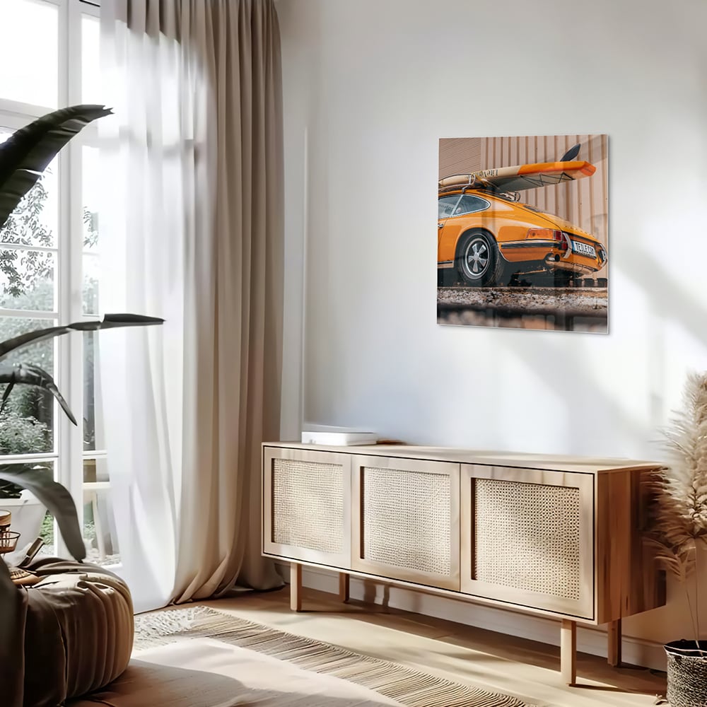 Een glazen schilderij van een oranje auto met een surfbord op het dak, gepresenteerd in een moderne woonkamer.