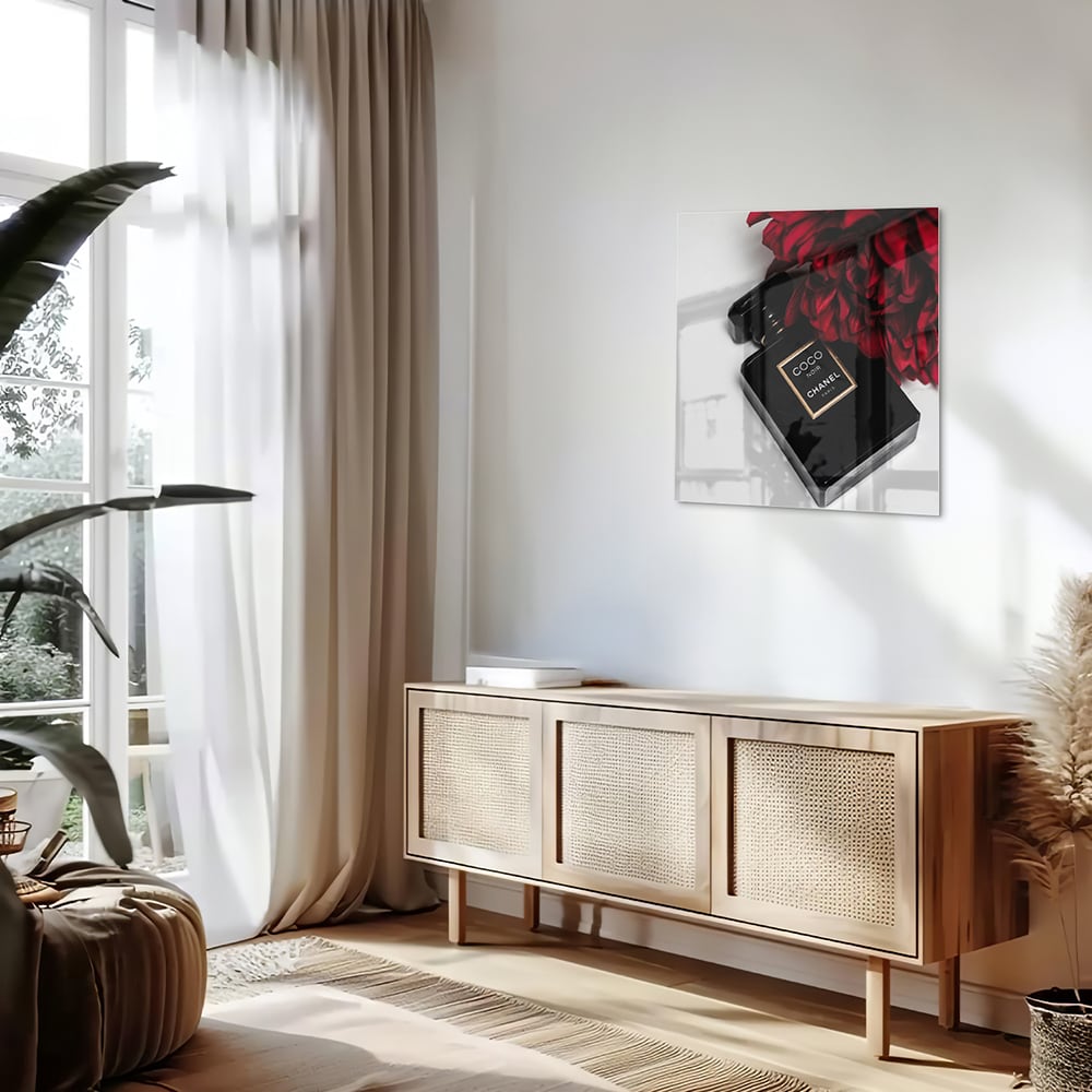 Glazen schilderij van parfumfles met rode bloemen op een witte muur