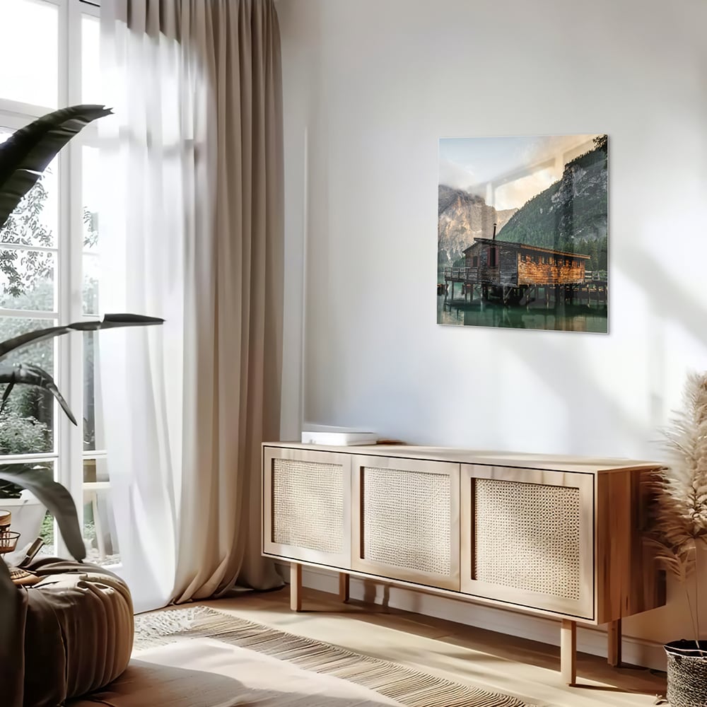 Glazen schilderij van een berghut aan een kalm meer met bergen op de achtergrond.