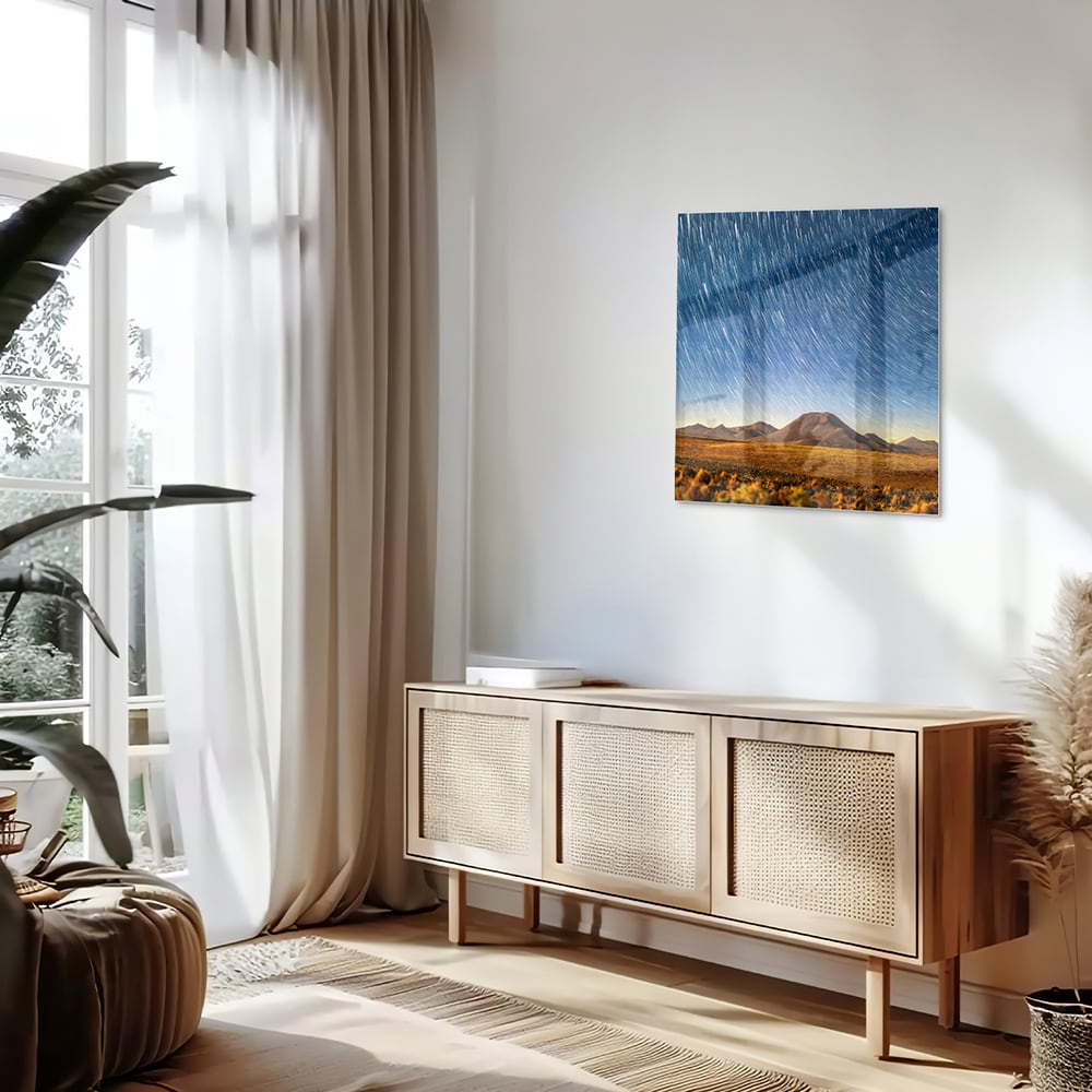 Glazen schilderij met sterrenhemel boven bergen, hangend aan de muur.