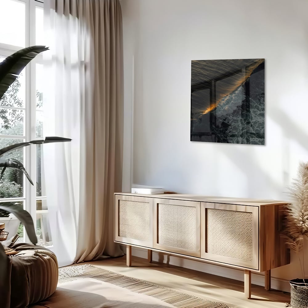 Zwart glazen schilderij van een zeegezicht met gouden accenten, hangt aan een lichtgekleurde muur.