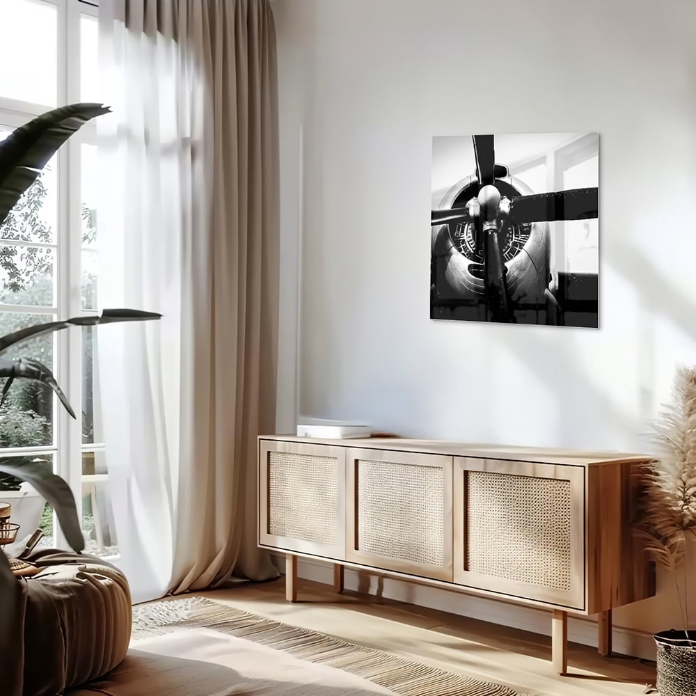 Zwart-wit glazen schilderij van een vintage vliegtuigpropeller tegen een lichte muur.