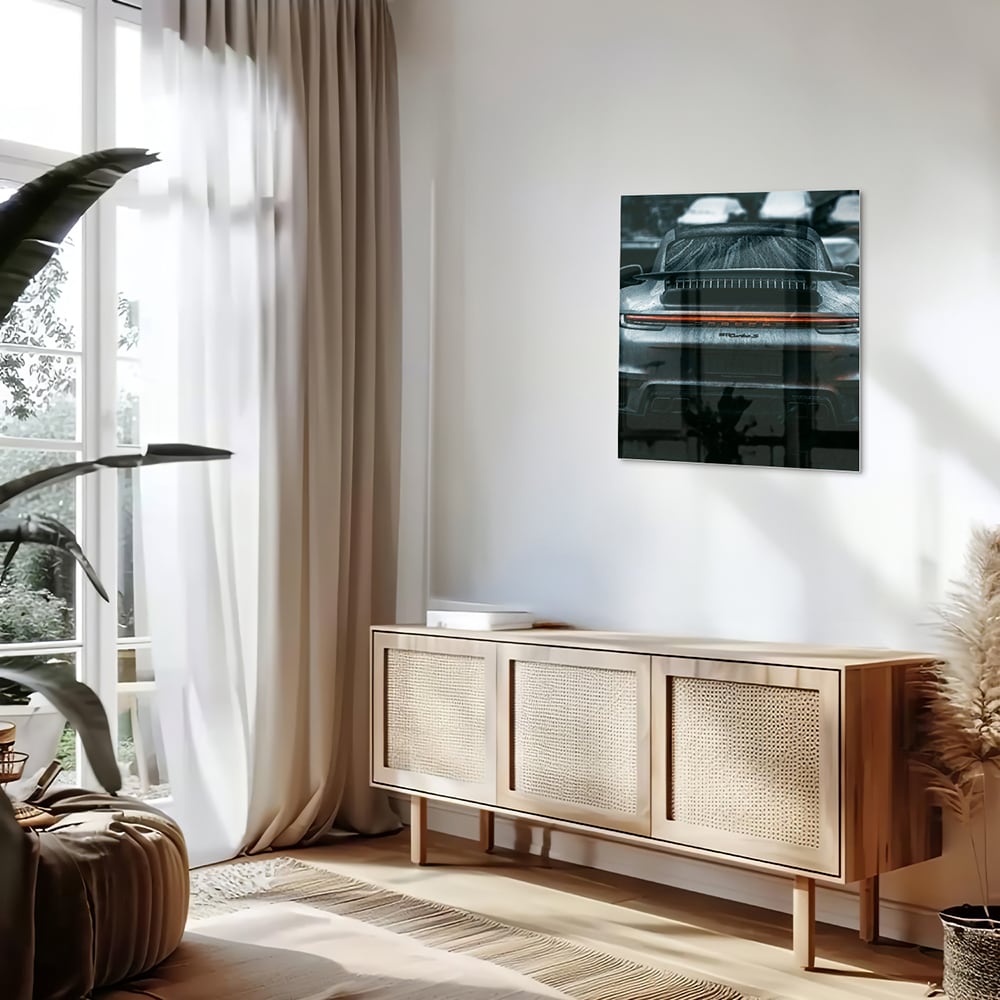 Glazen schilderij van een sportwagen aan de muur in een lichte woonkamer.