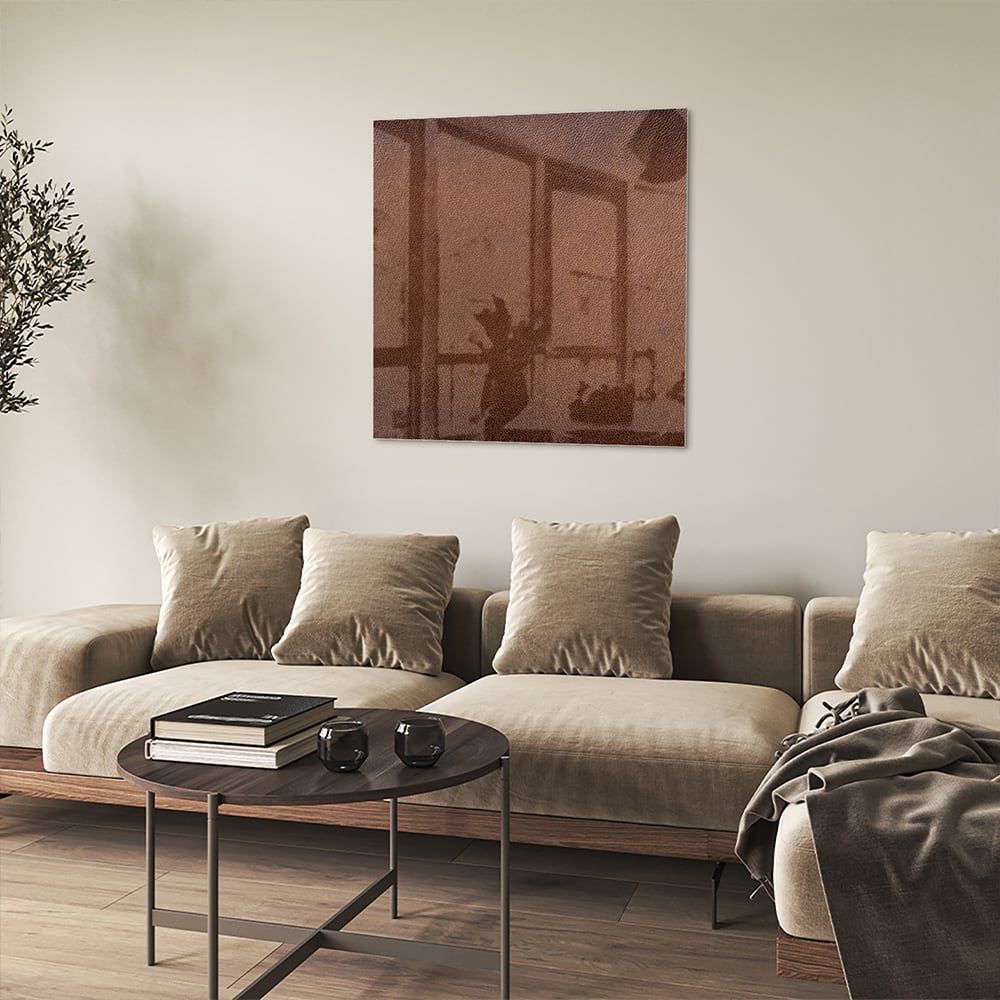 Glazen schilderij in aardetinten, op een witte muur boven een houten meubel.