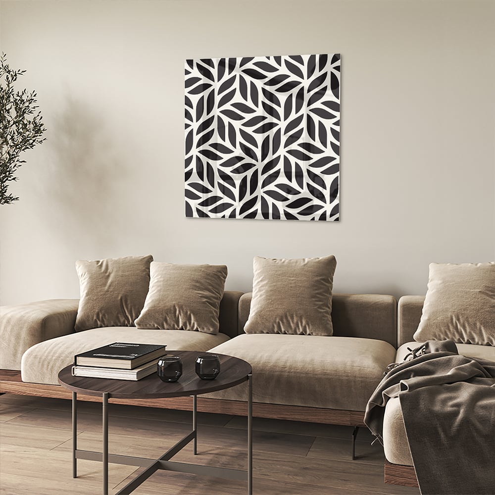 Zwart-wit glazen schilderij met bladerenpatroon aan de muur in een moderne woonkamer.
