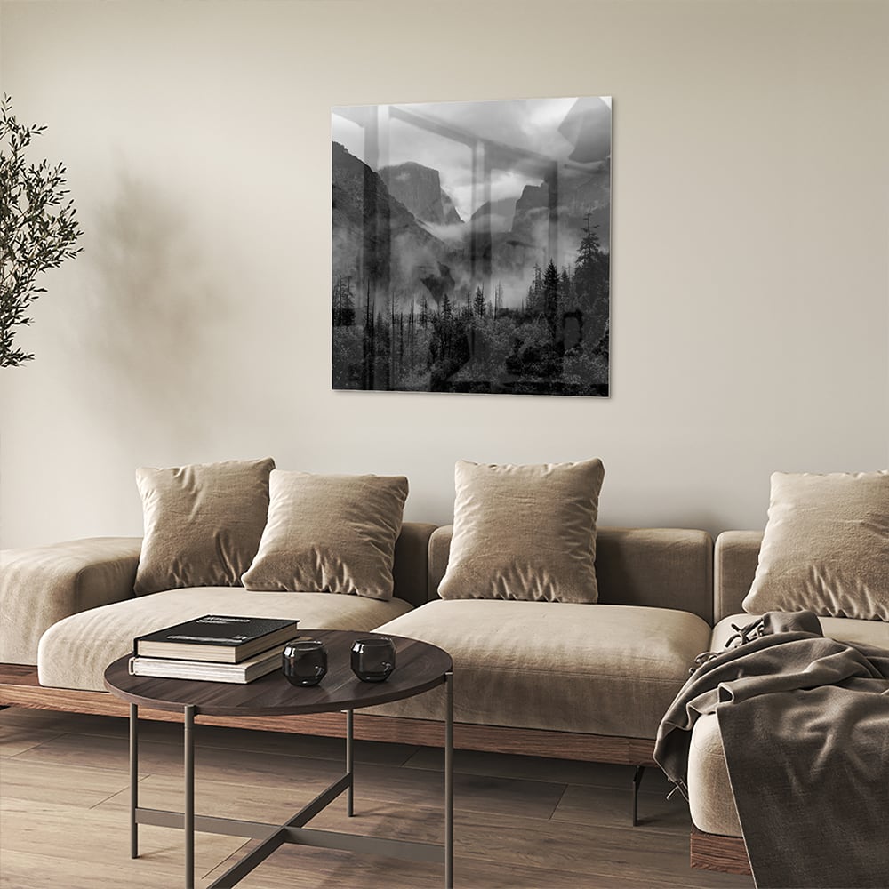 Zwart-wit glazen schilderij van een sereen berglandschap aan de muur.