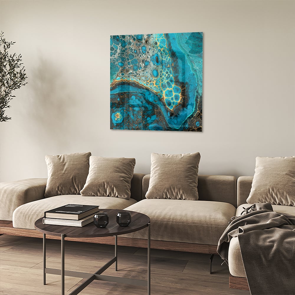 Glazen schilderij in turkoois met gouden accenten aan de muur boven een houten meubel.