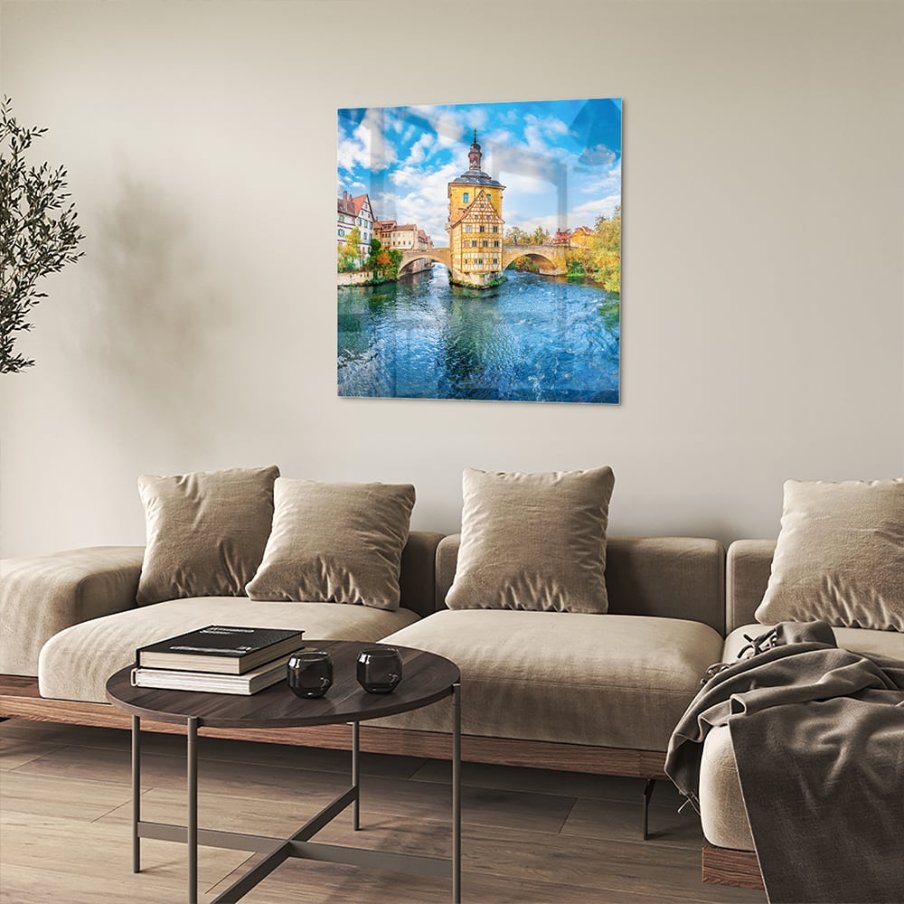 Glazen schilderij van een schilderachtig stadje aan het water met kleurrijke gebouwen en een helderblauwe lucht.