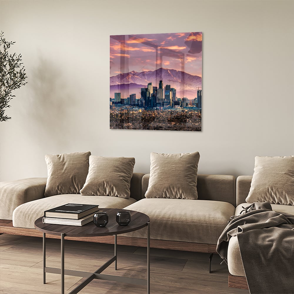 Glazen schilderij van een stadspanorama bij zonsondergang met bergen op de achtergrond.