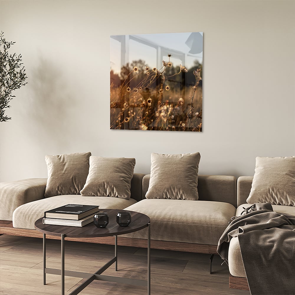 Glazen schilderij van een zonsondergang met bloeiende bloemen, hangend aan een witte muur.