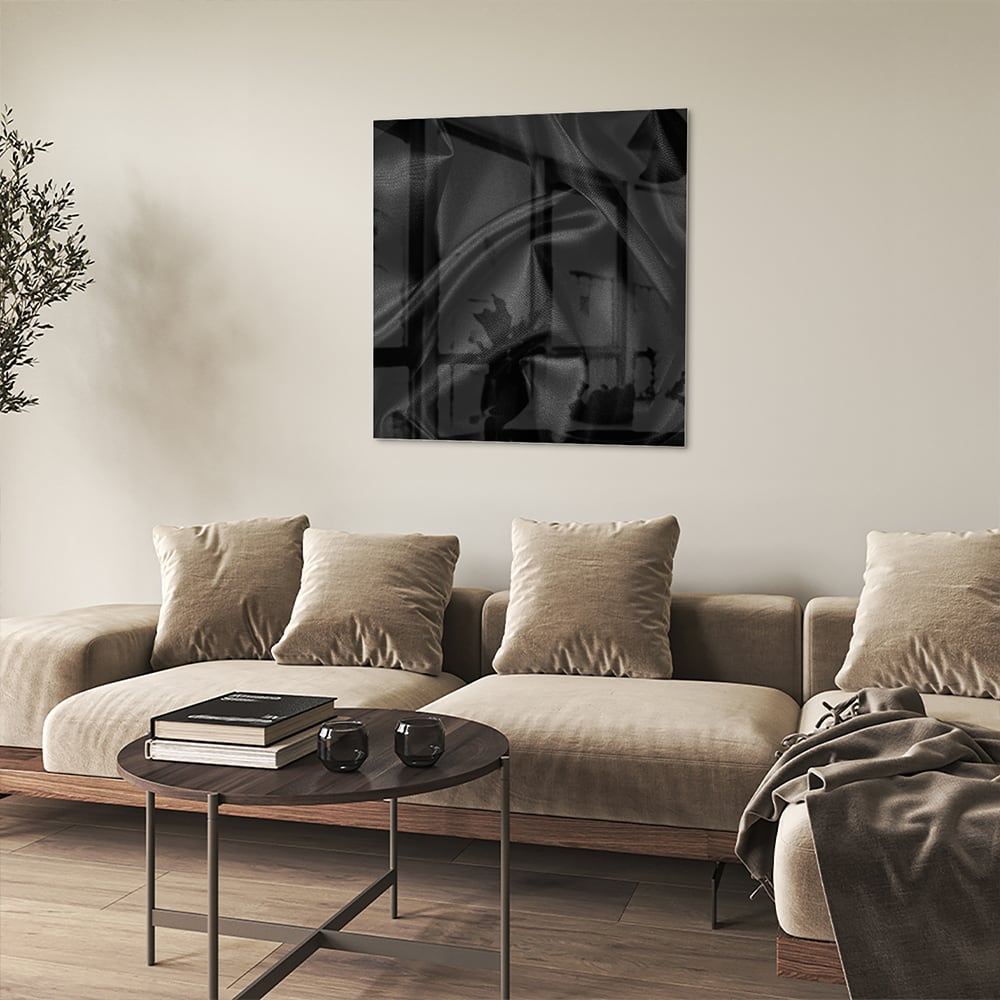Een zwart glazen schilderij hangt aan de muur van een moderne woonkamer.