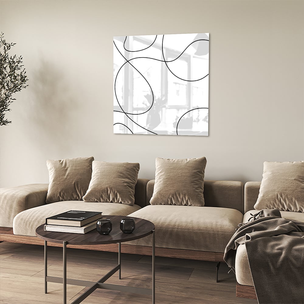 Glazen schilderij met elegante zwarte lijnen in een moderne woonkamer.