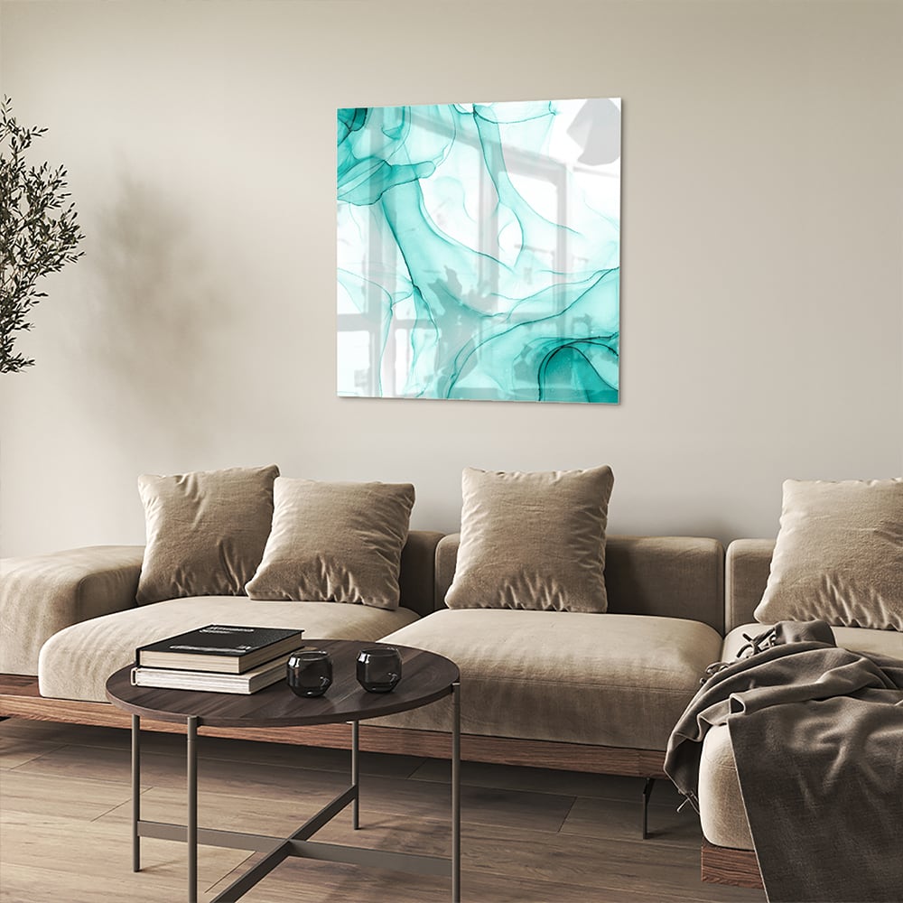 Lichtblauw abstract glazen schilderij aan de muur boven een houten meubel.