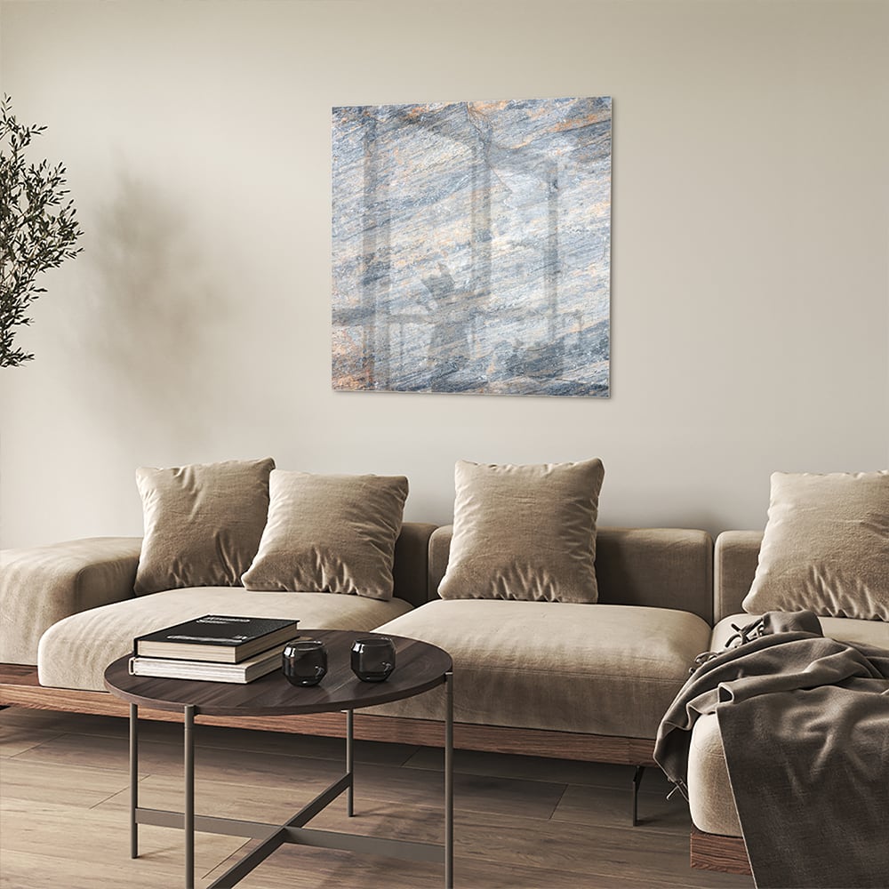 Abstract glazen schilderij met blauwe en oranje tinten aan de muur in een moderne woonkamer.