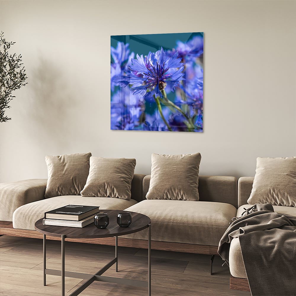 Een glazen schilderij met paarse bloemen op een witte muur, in een sfeervolle woonkamer.