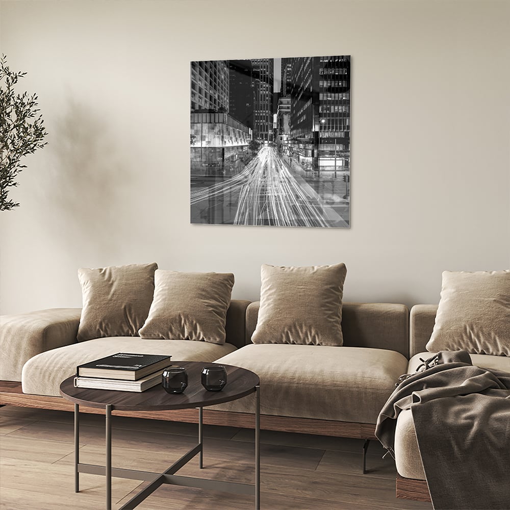 Glazen schilderij met stadslichten in zwart-wit boven een moderne meubelset.