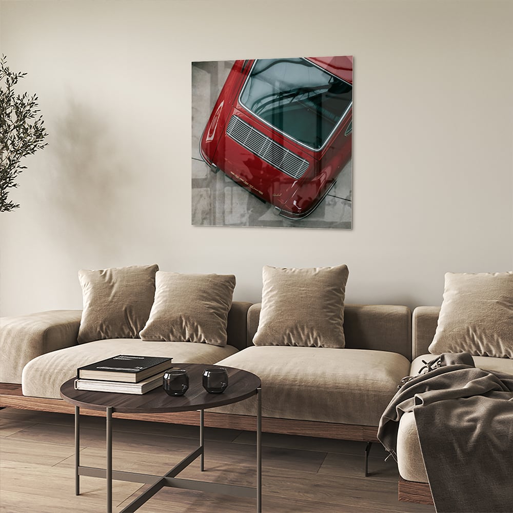 Glazen schilderij van een bovenaf gezien rode auto op een muur.