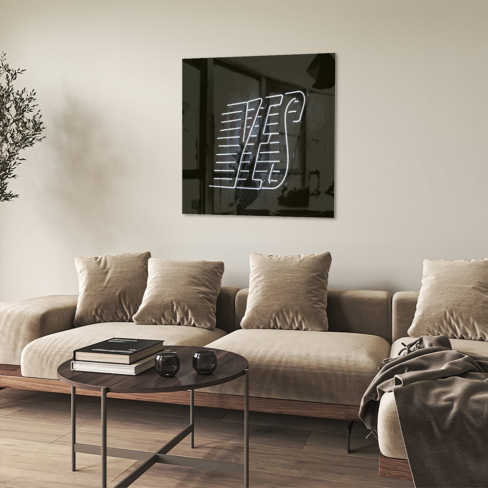 Glazen schilderij met 'YES' text in zwart en wit, hangend aan de muur.
