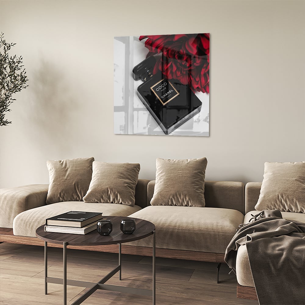 Glazen schilderij van parfumfles met rode bloemen op een witte muur