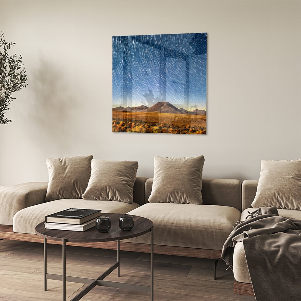 Glazen schilderij met sterrenhemel boven bergen, hangend aan de muur.