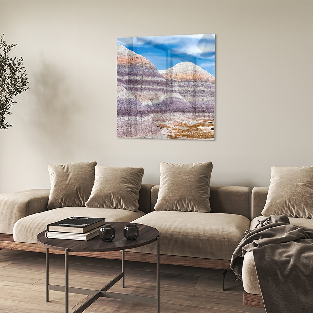 Glazen schilderij van bergen met een blauwe lucht in een moderne woonkamer.