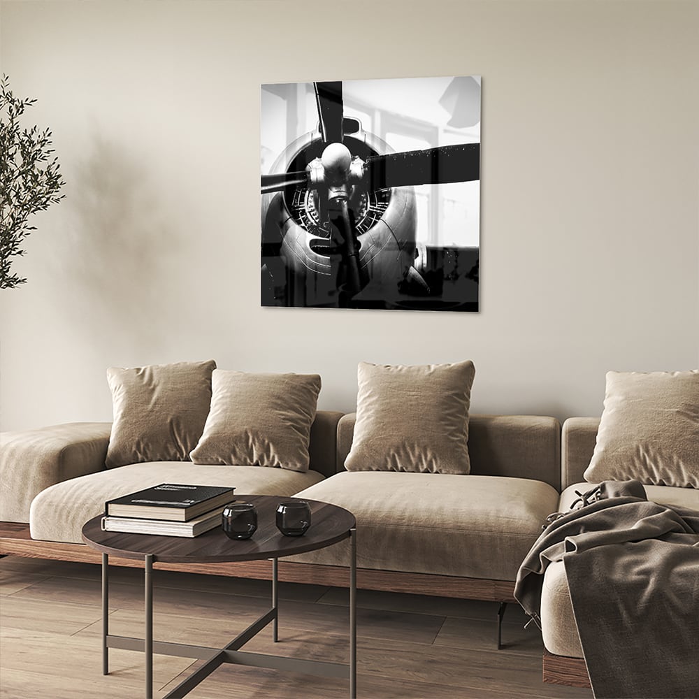 Zwart-wit glazen schilderij van een vintage vliegtuigpropeller tegen een lichte muur.