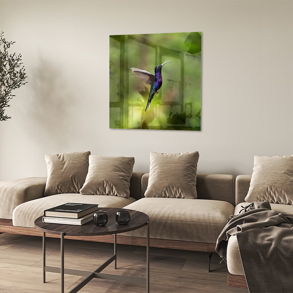 Een glazen schilderij van een kolibrie die vloog voor een groene achtergrond in een lichte kamer.