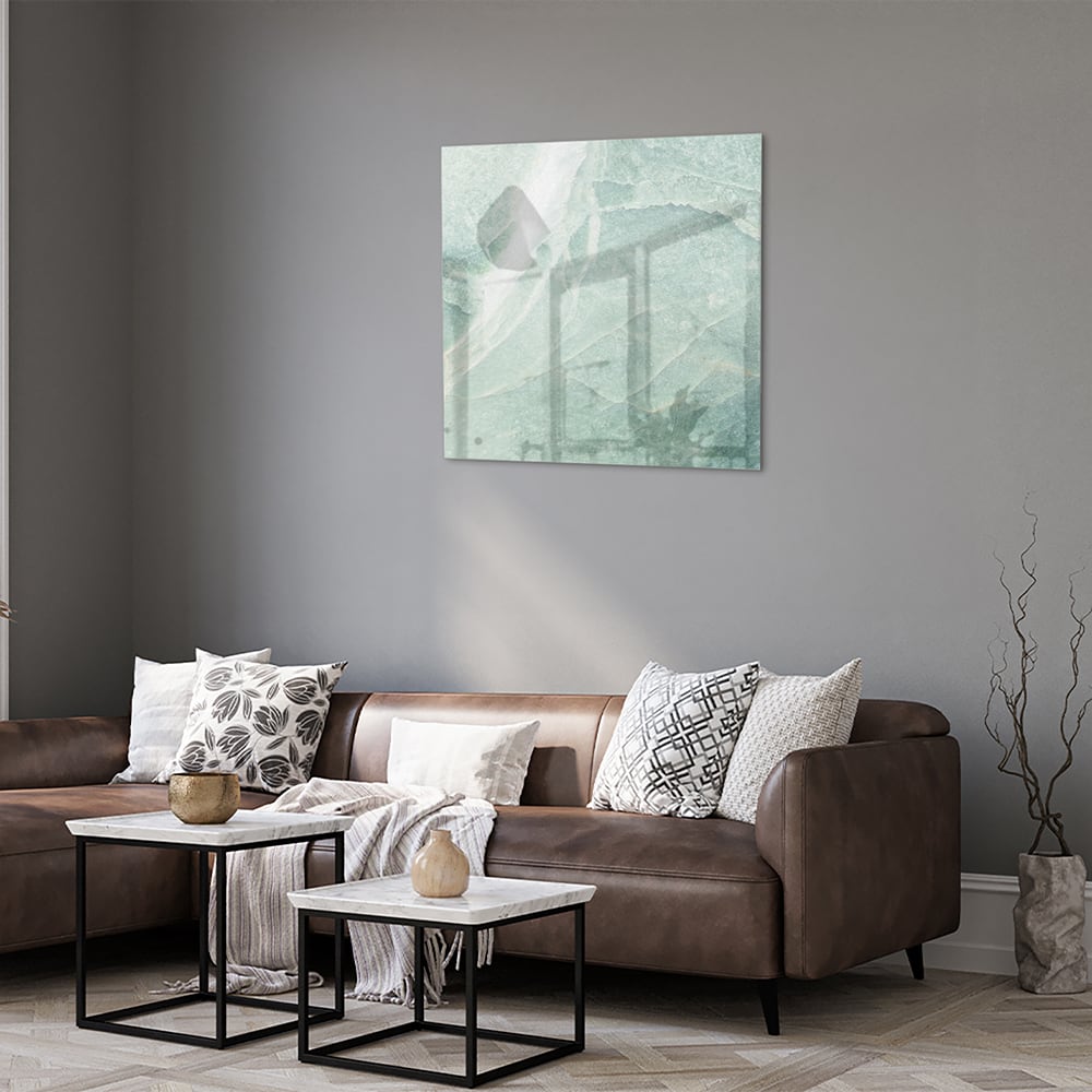 Abstract groen glazen schilderij aan de muur boven een houten meubel.