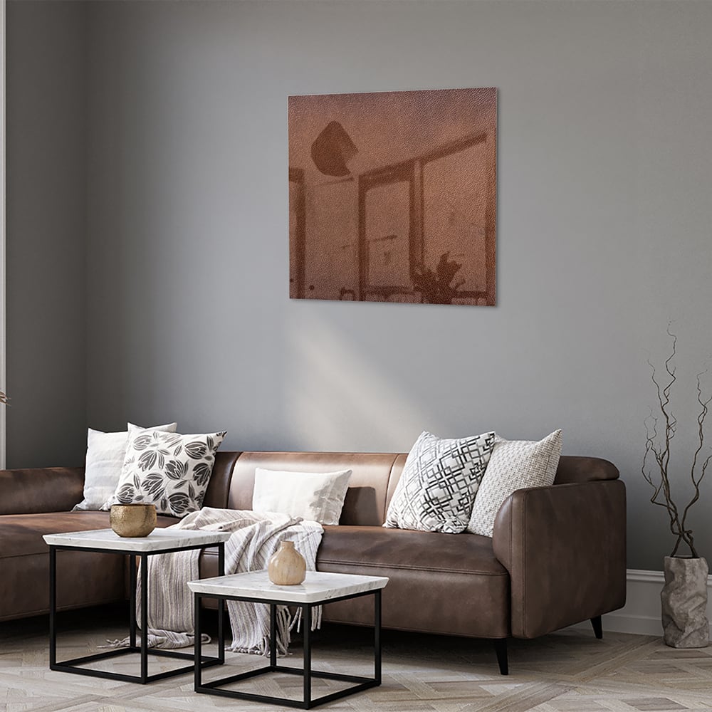 Glazen schilderij in aardetinten, op een witte muur boven een houten meubel.