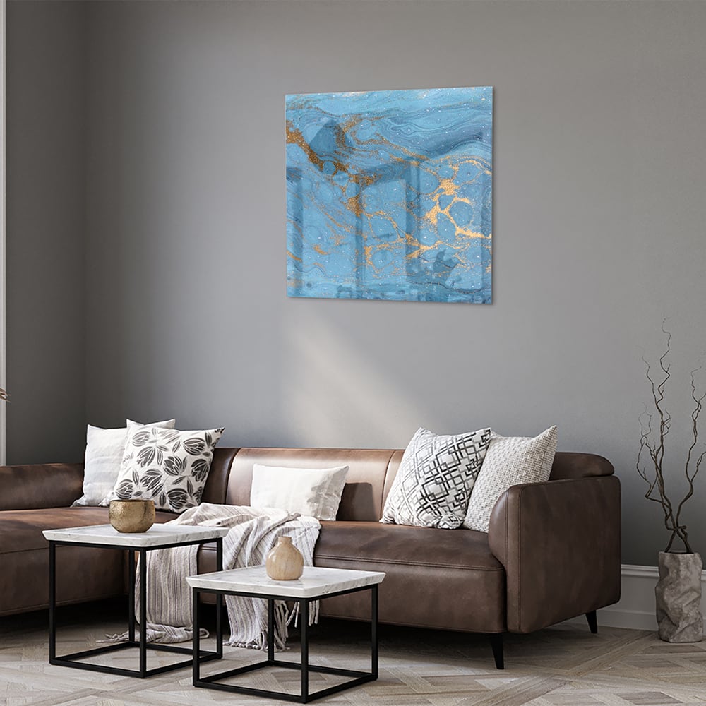 Glazen schilderij met blauw en gouden patronen aan de muur boven een houten kast.