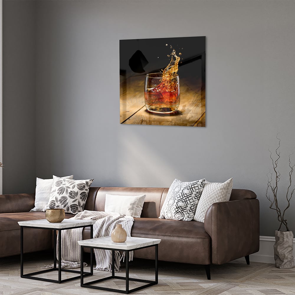 Glazen schilderij met een glas en spetterende drank op een houten tafel.