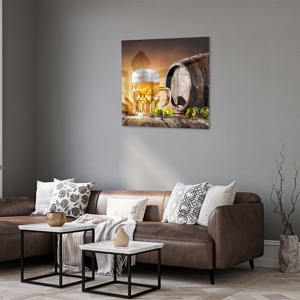 Glazen schilderij van een koud biertje op een houten tafel met groen in de achtergrond.