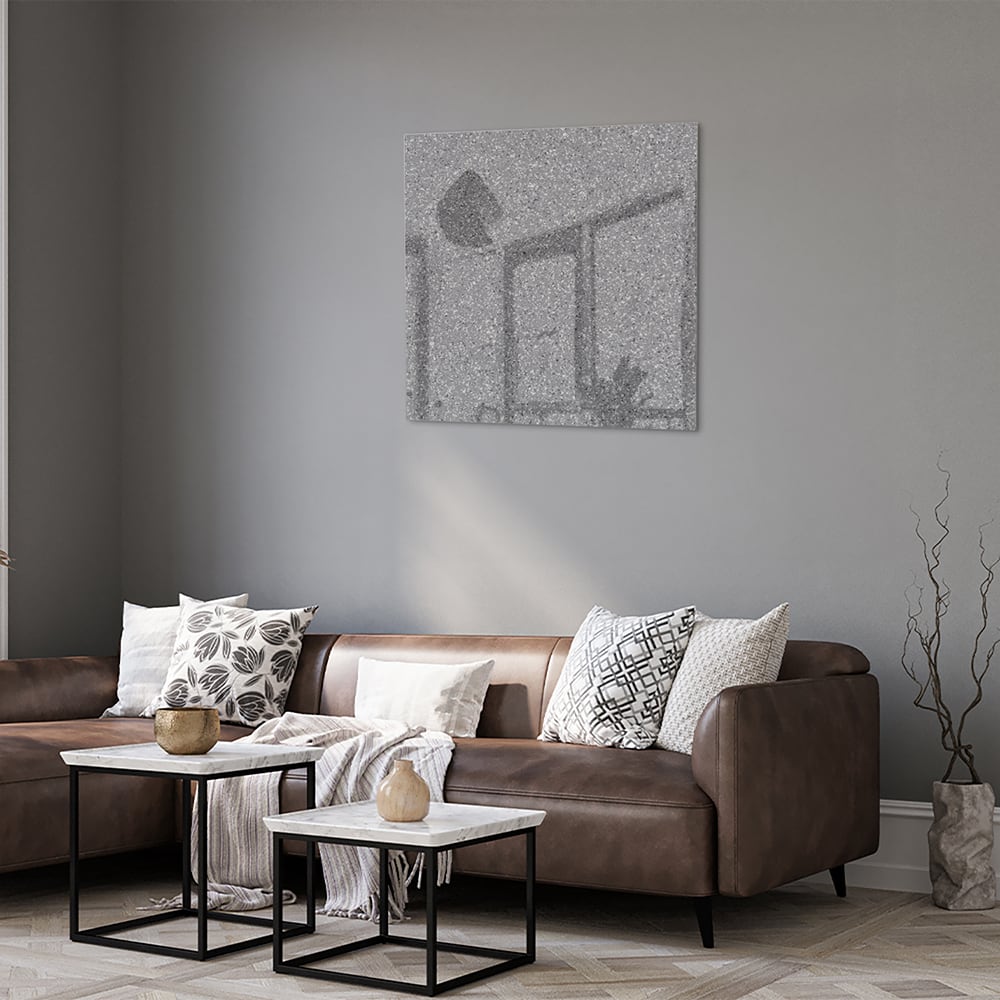 Abstract glazen schilderij in grijstinten hangt aan de muur in een moderne woonkamer.