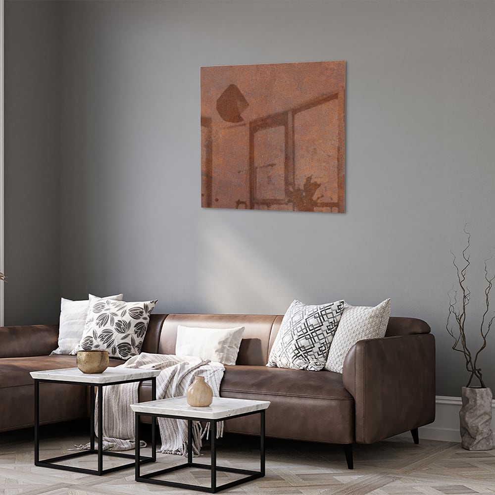 Abstract glazen schilderij met aardetinten boven een houten meubel.