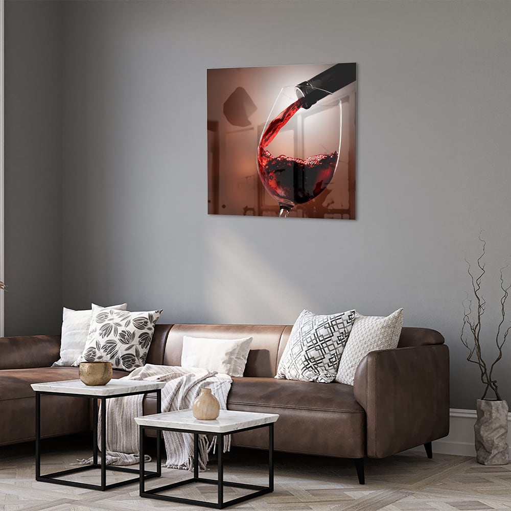 Glazen schilderij van een rode wijn die in een glas wordt ingeschonken, zichtbaar in een moderne woonkamer.