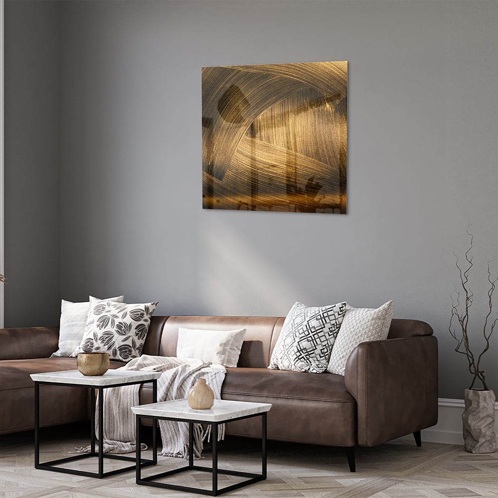 Glazen schilderij met gouden patronen aan de muur boven een houten meubel.
