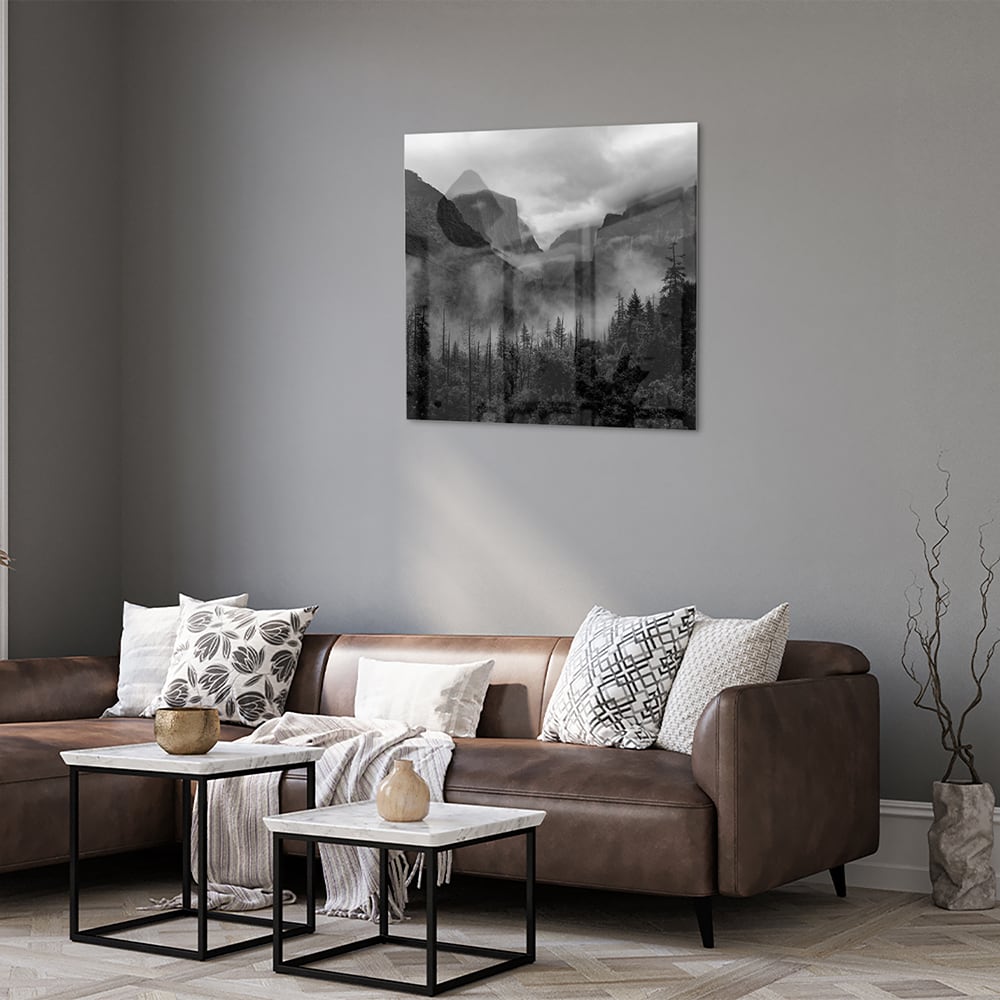 Zwart-wit glazen schilderij van een sereen berglandschap aan de muur.