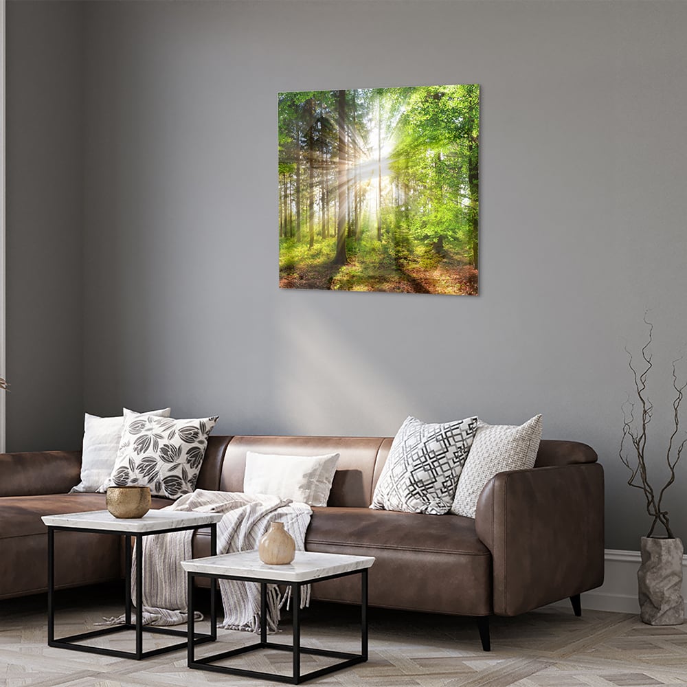 Glazen schilderij van een bos met zonnestralen op een muur.