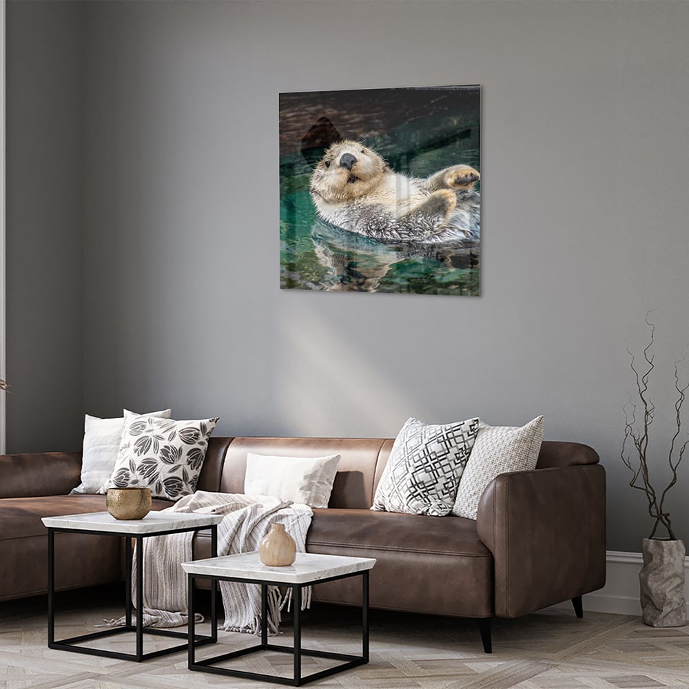 Glazen schilderij van een zeeotter die in water drijft.