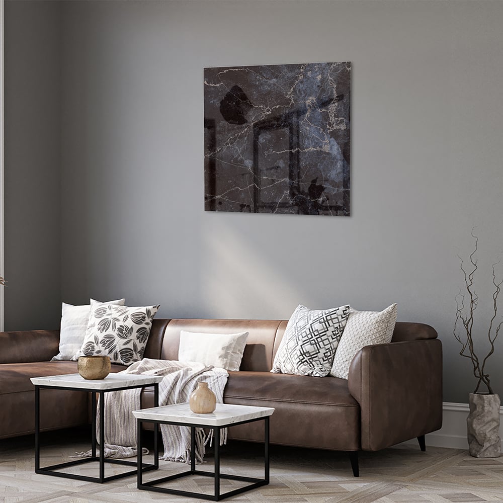 Glazen schilderij met donker marmerlook aan een lichte muur in een moderne woonkamer.