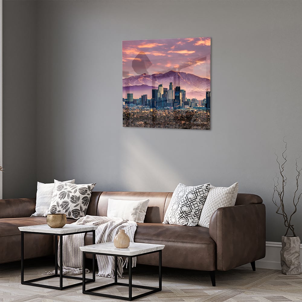 Glazen schilderij van een stadspanorama bij zonsondergang met bergen op de achtergrond.