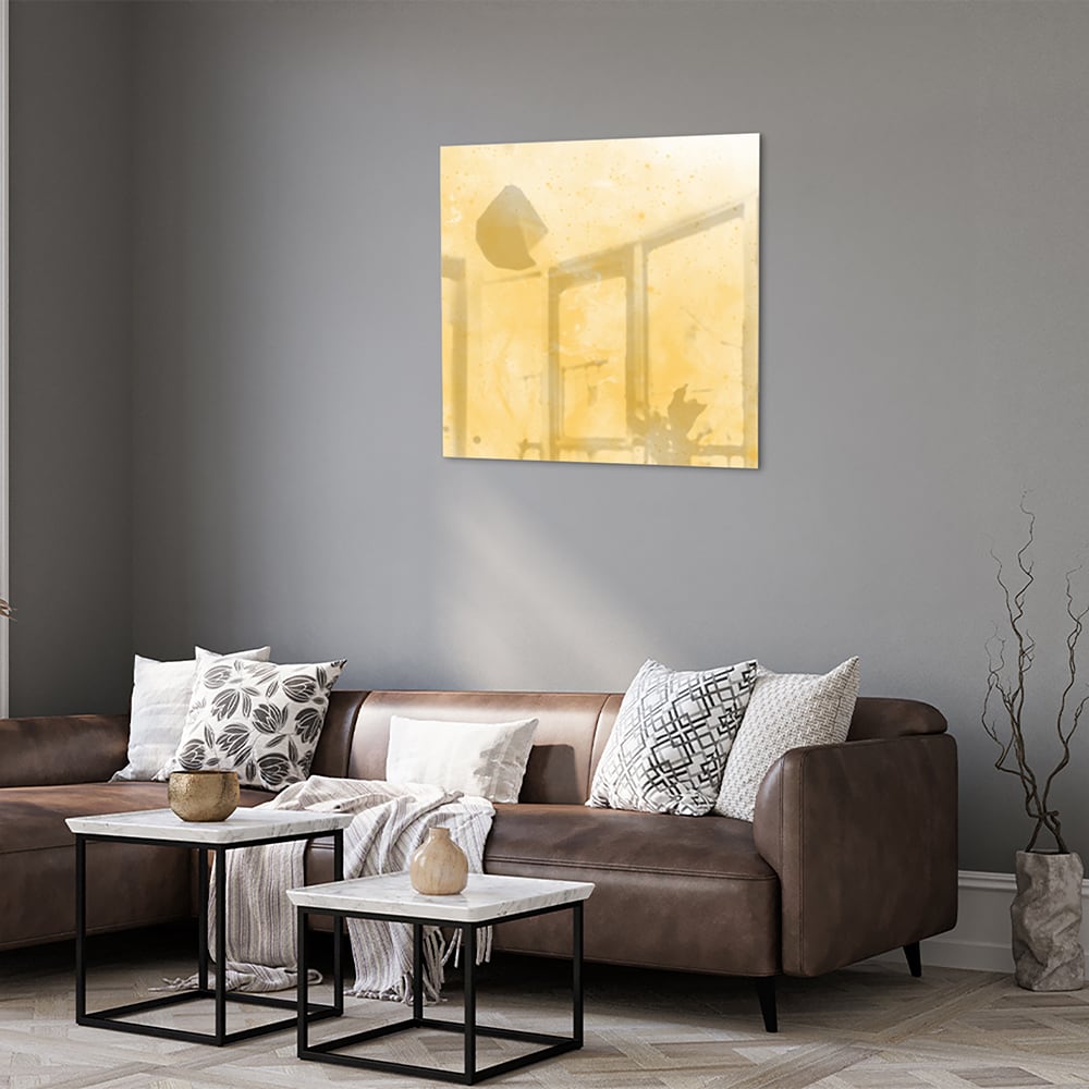 Abstract glazen schilderij in gouden tinten op een witte muur in een moderne woonkamer.