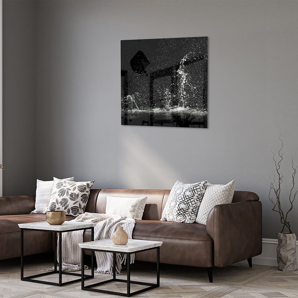 Zwart-wit glazen schilderij met een dynamisch spatwatereffect aan de muur.
