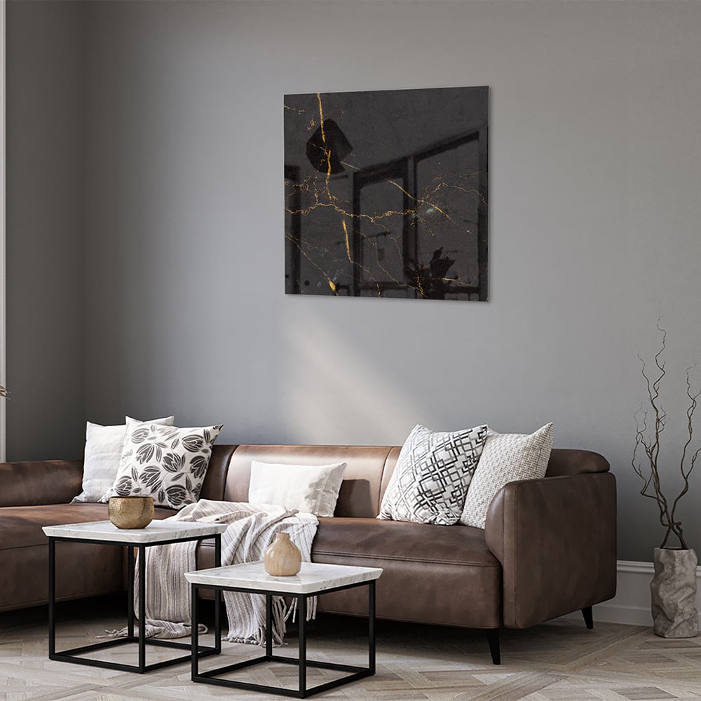 Zwart glazen schilderij met gouden lijnen aan de muur in een moderne woonkamer.
