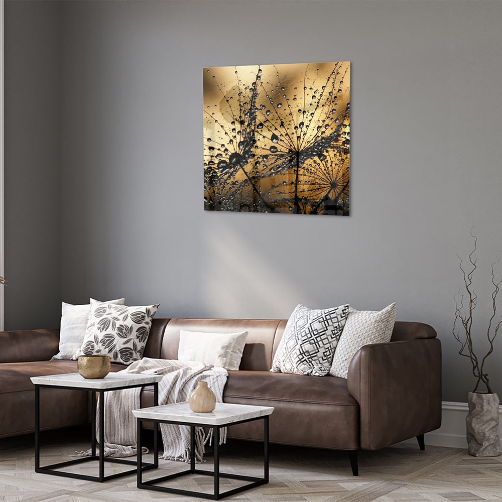 Glazen schilderij met gouden waterdruppels op een lichte muur.